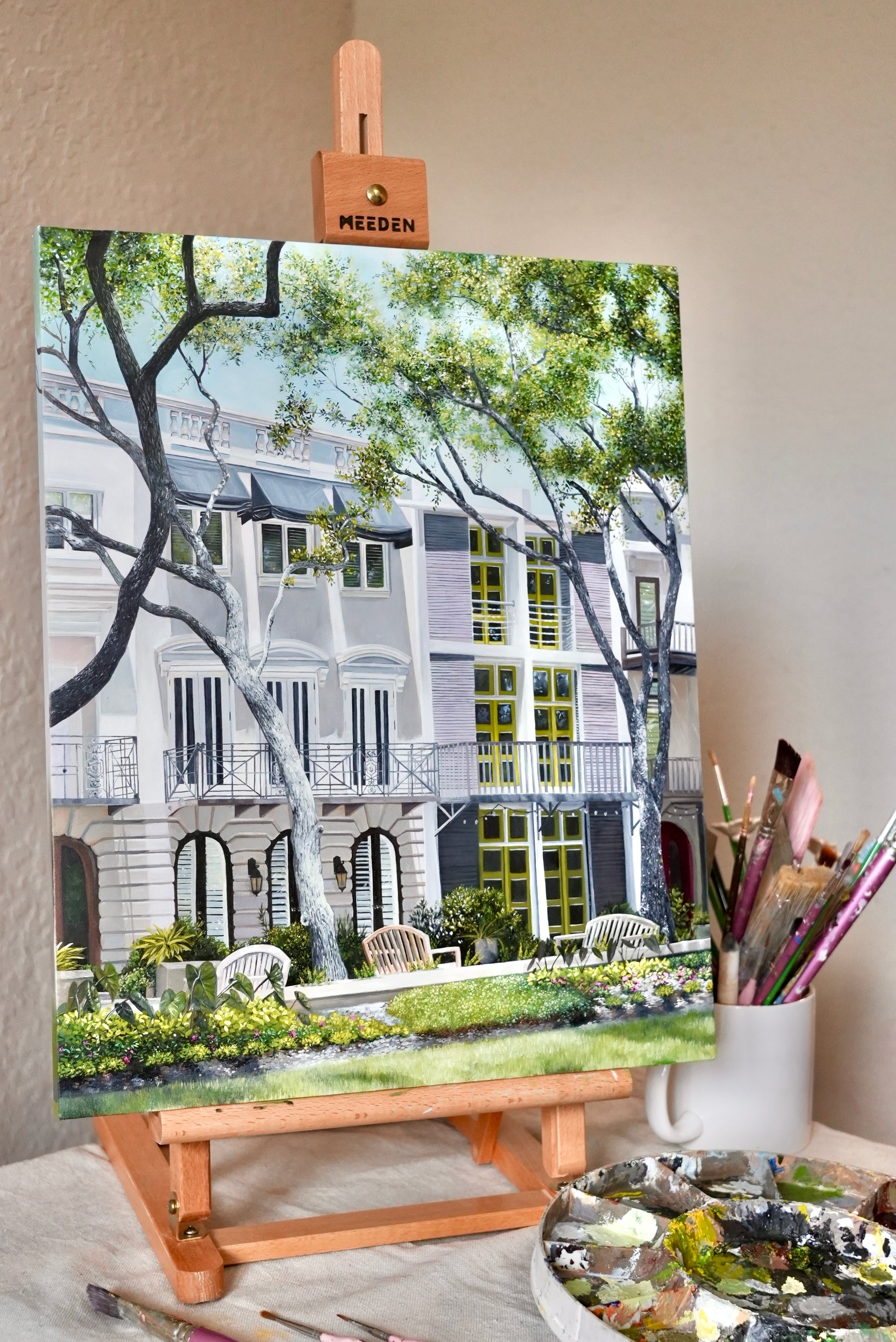 Painting of a residential street scene on an easel with art supplies.