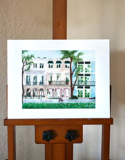 artwork of a building on a wooden easel against a plain wall.