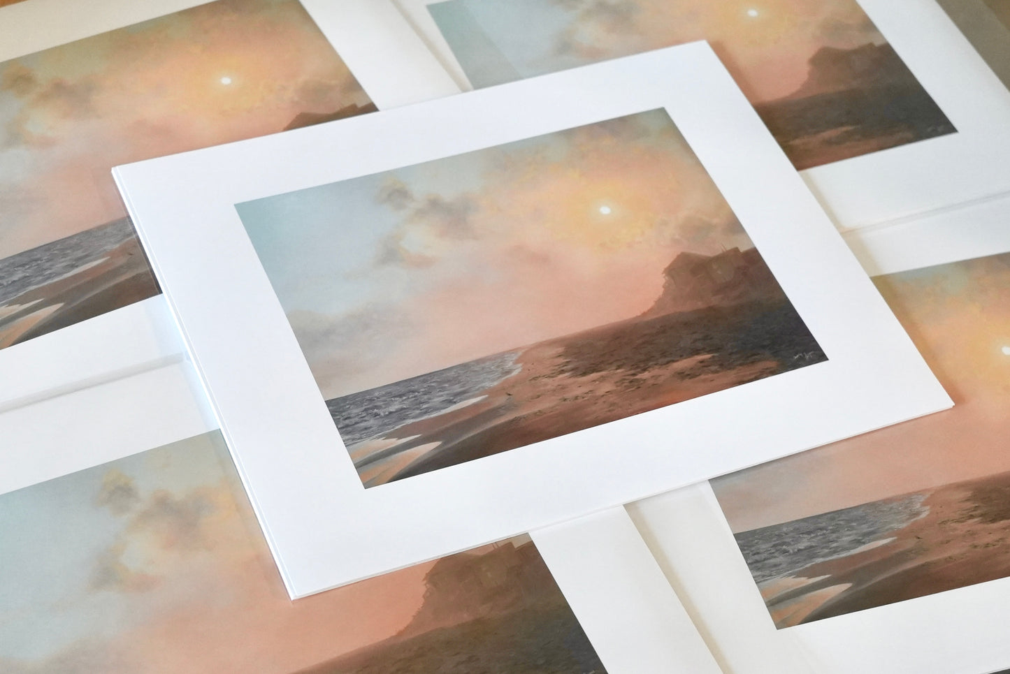 Stack of prints with a beachy landscape.
