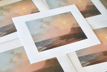 Stack of prints with a beachy landscape.