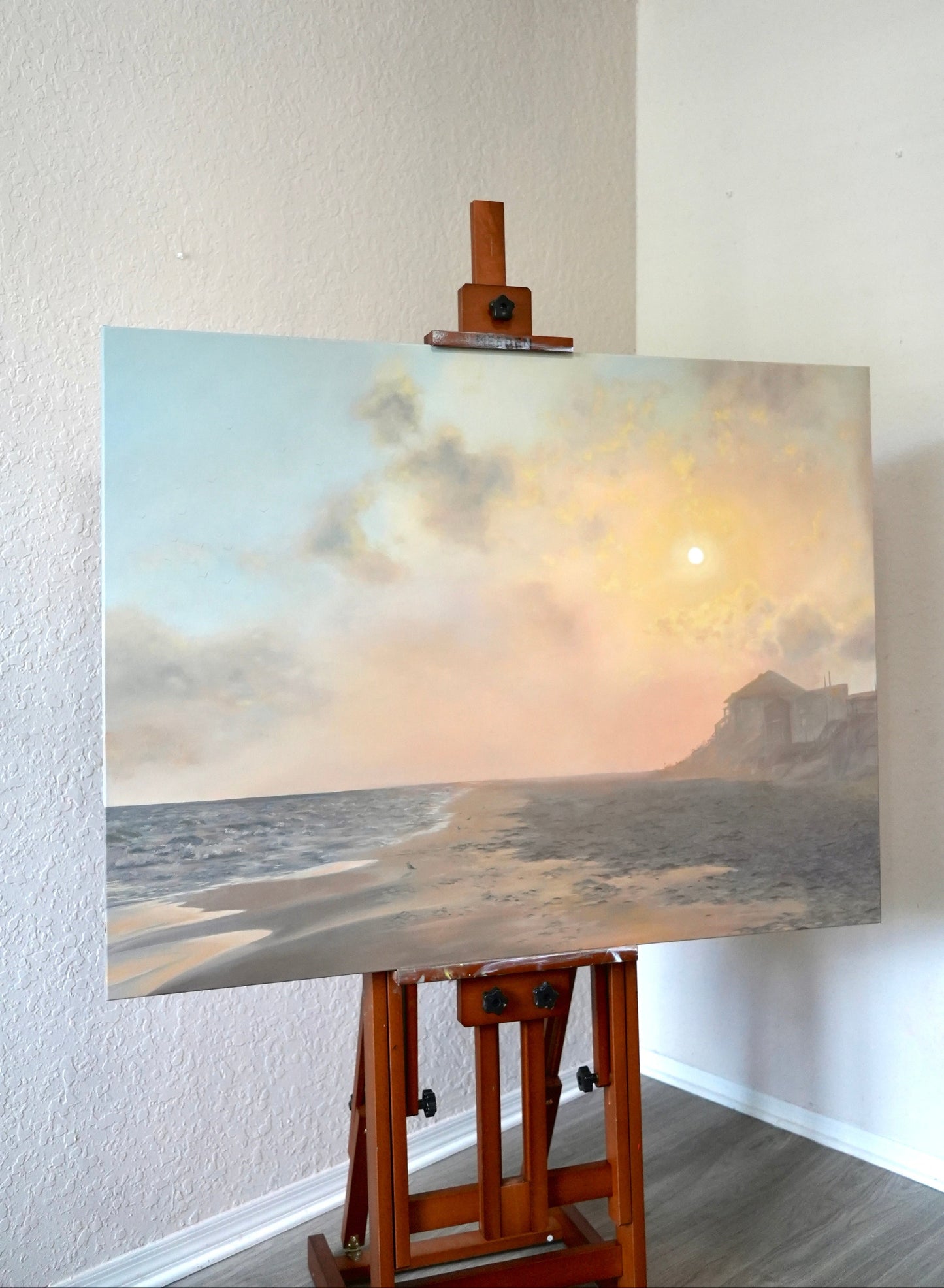 Painting of a coastal scene on an easel against a white wall