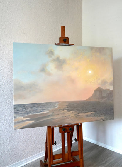 Painting of a coastal scene on an easel against a white wall