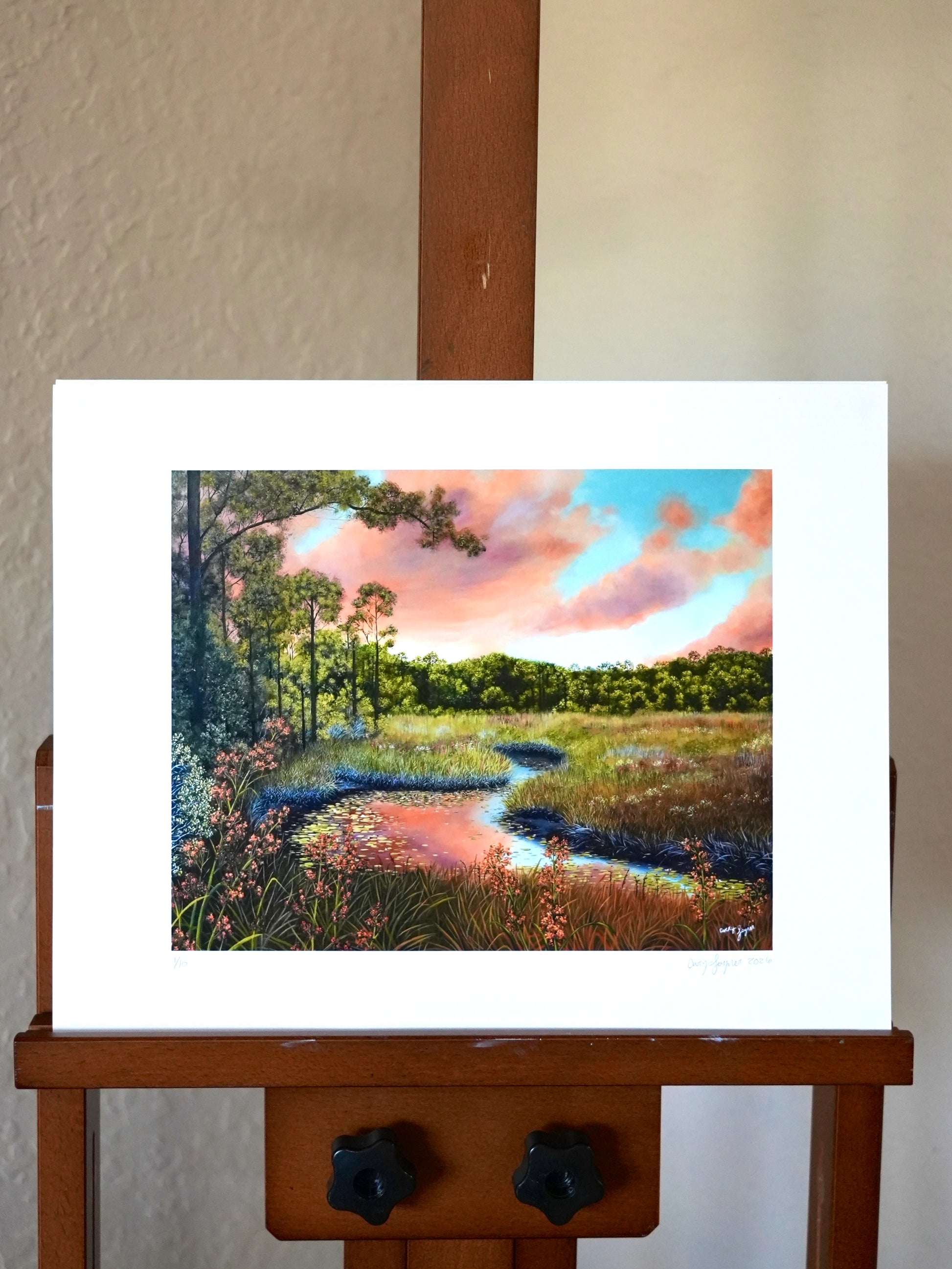 Painting of a landscape with trees and a sky on an easel.