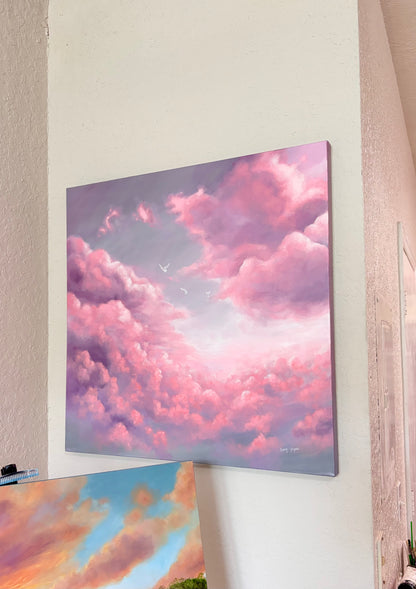 Canvas painting of a pink and purple cloud sky hanging on a wall.