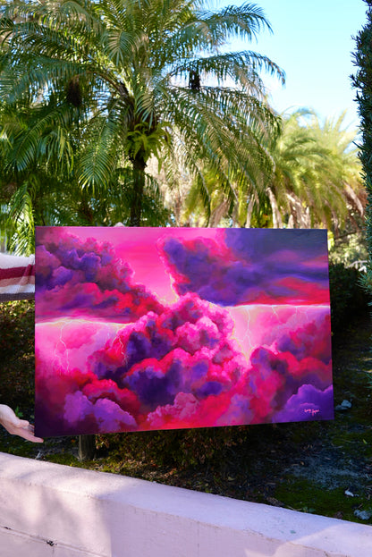 Colorful cloud painting displayed outdoors with palm trees in the background