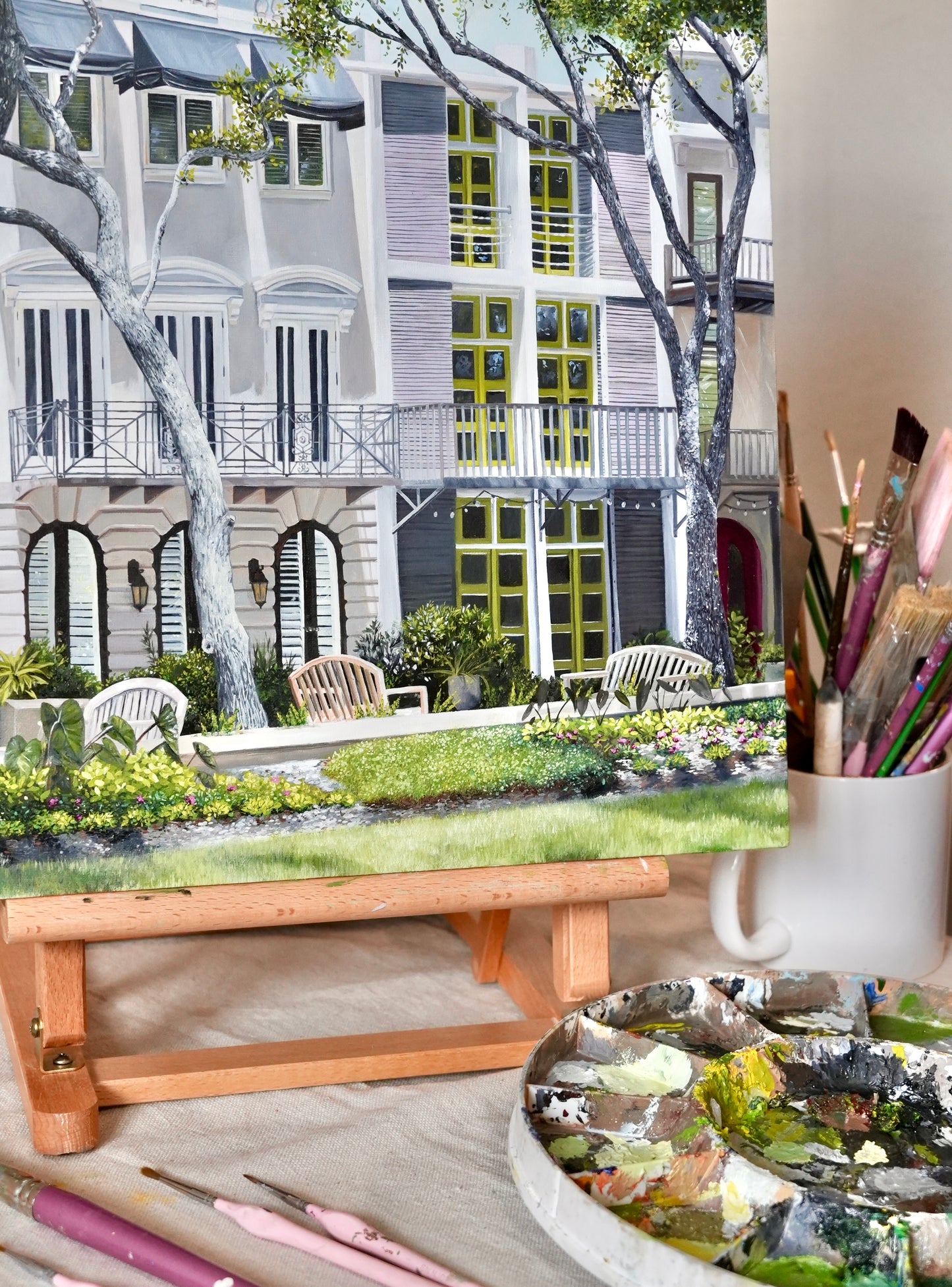 Artistic depiction of a garden scene with a table, paintbrushes, and a palette.