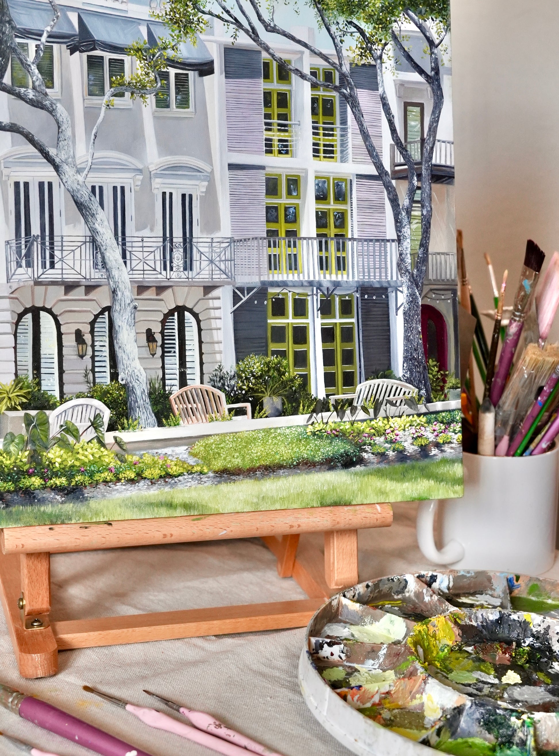 Artistic depiction of a garden scene with a table, paintbrushes, and a palette.