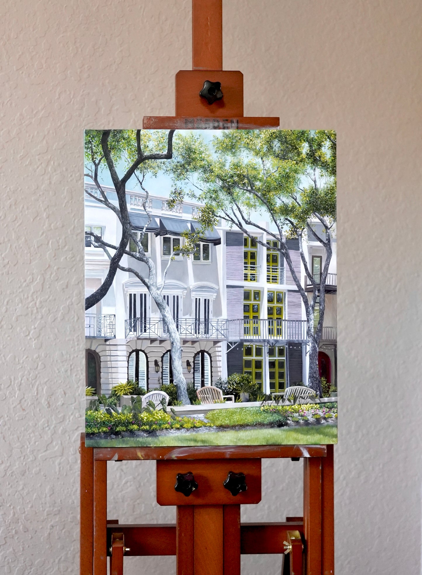 Painting of a courtyard scene on an easel against a white wall